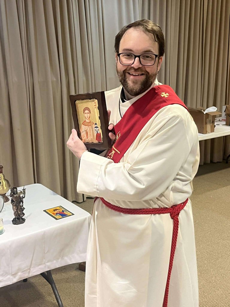 A deacon holding a painted icon during a service.