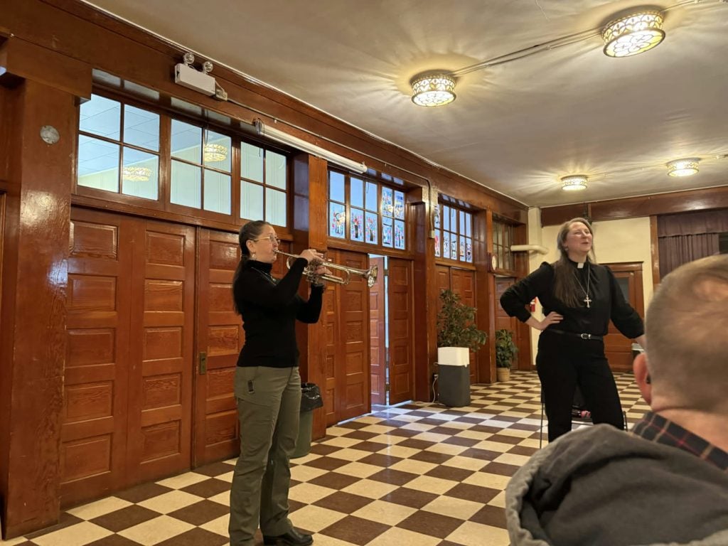 A trumpeter playing during a gathering in the fellowship hall.